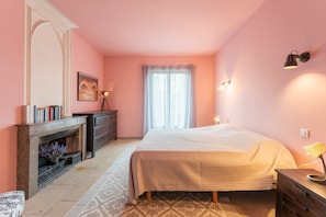 Une chambre à coucher avec un lit, une commode, un miroir et une cheminée.