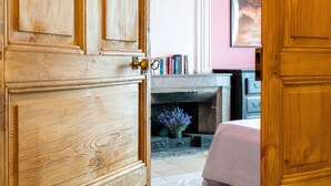 Una puerta de madera con manija de latón, una chimenea con una manta rosa y una estantería llena de libros.