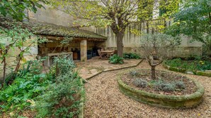 Un patio con una mesa de piedra, un árbol y un muro de piedra.