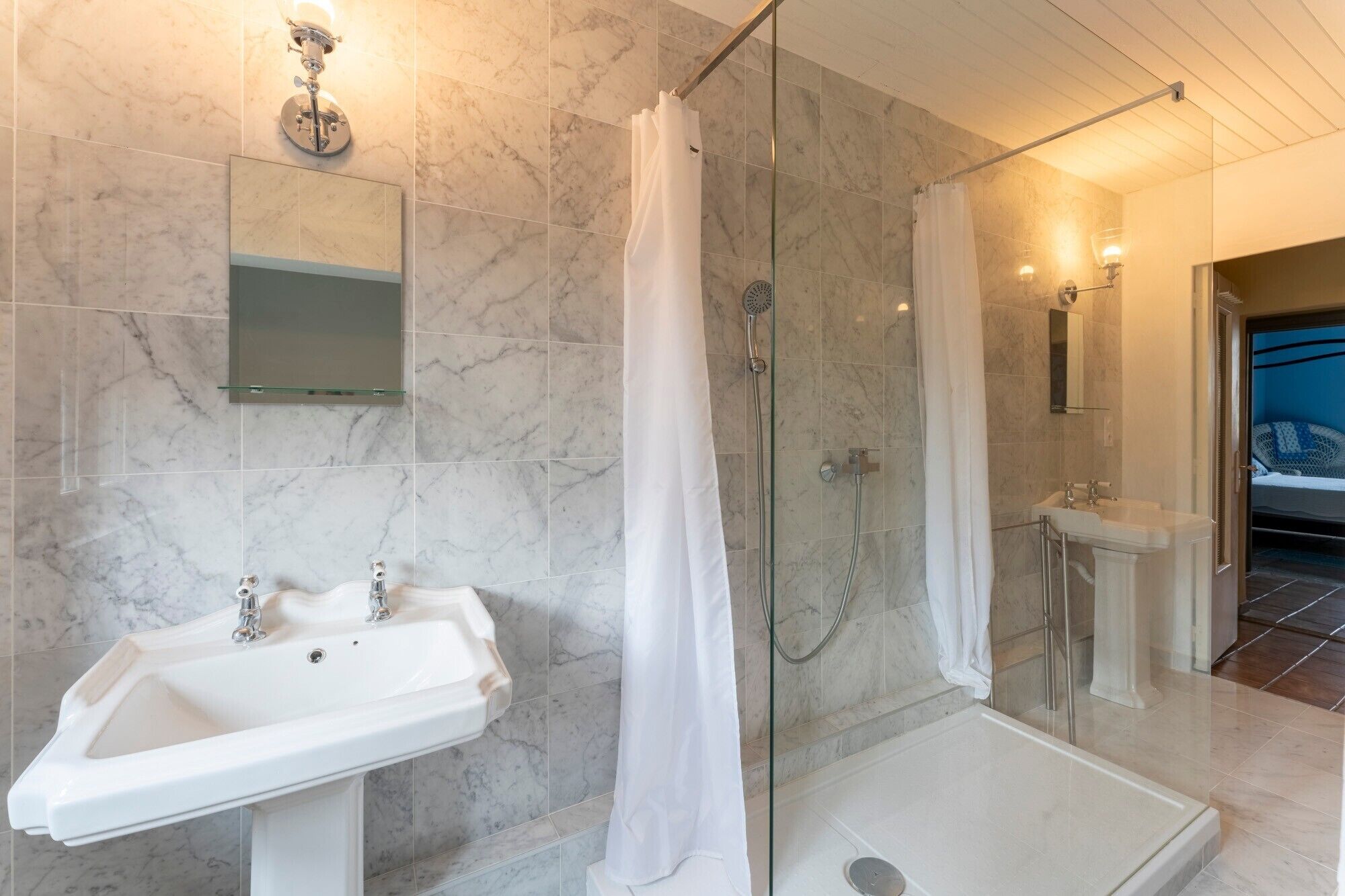 Un bagno con box doccia in vetro, lavandino e specchio.