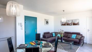 A modern living room with a glass dining table, a sofa, and a blue door.