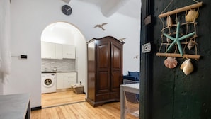 A kitchen with wooden flooring, a washing machine, and a cabinet. - Apartment 'Baia Del Silenzio Beach' with Wi-Fi and Air Conditioning (Sestri Levante)