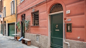 A narrow street with a red building featuring a green door, a bench, and a small table. - Apartment 'Baia Del Silenzio Beach' with Wi-Fi and Air Conditioning (Sestri Levante)