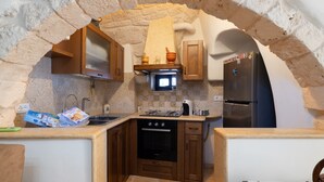 A kitchen with stone archway, wooden cabinets, a built-in oven, and a refrigerator. - Apartment 'La Dimora In Ostuni' with Air Conditioning (Ostuni)