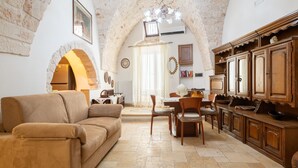 A cozy living room with a sofa, dining table, chairs, and a kitchen area with cabinets. - Apartment 'La Dimora In Ostuni' with Air Conditioning (Ostuni)