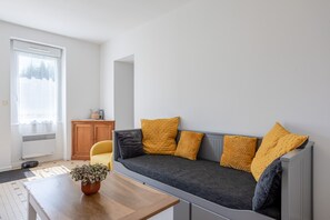 Uma sala de estar moderna com um sofá, um armário de madeira e uma planta em vaso.