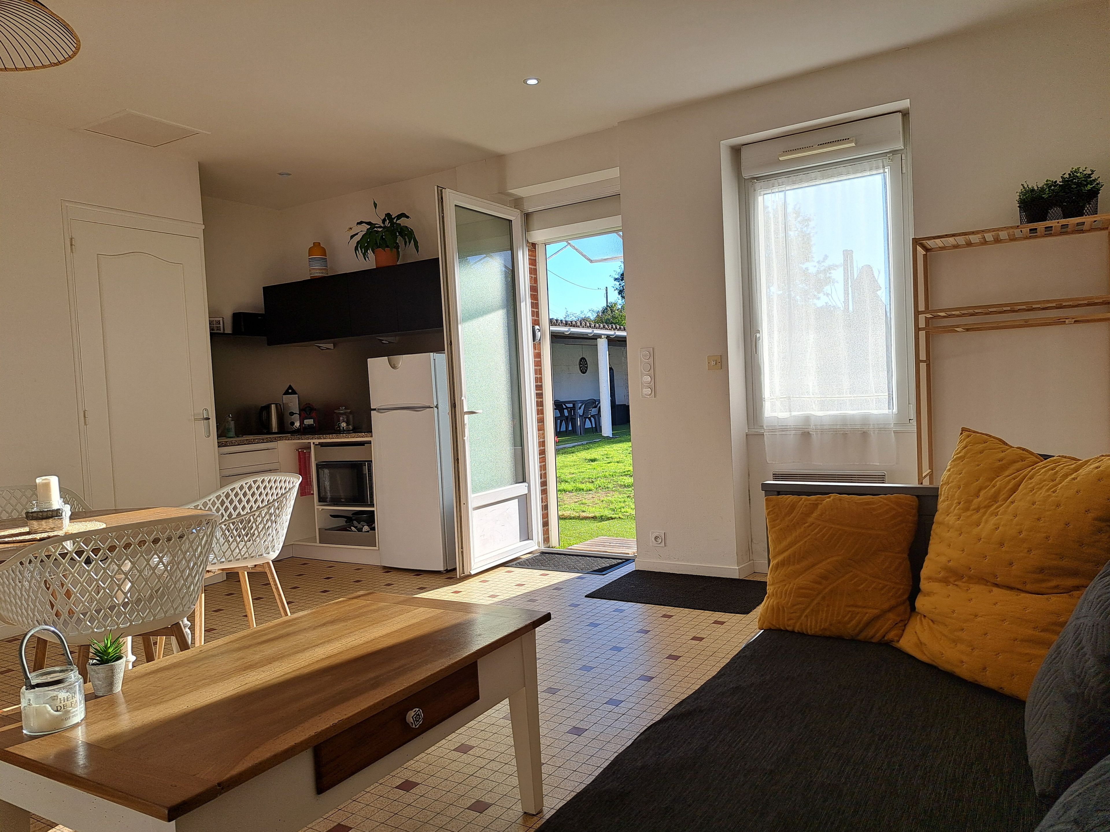 A modern living room with a sofa, a dining table, and a kitchen area.