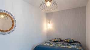 Un dormitorio con una cama, un banco de madera, un espejo en la pared y un candelabro en el techo.