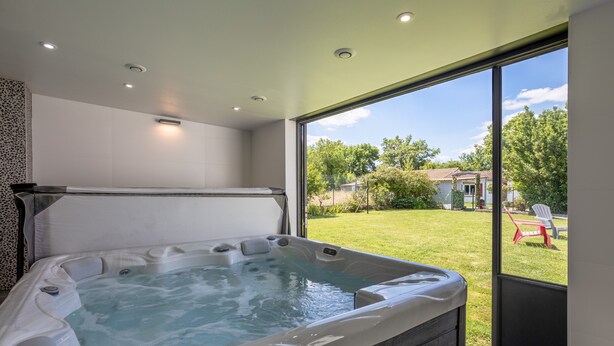 Un jacuzzi con vista a un jardín césped y árboles.