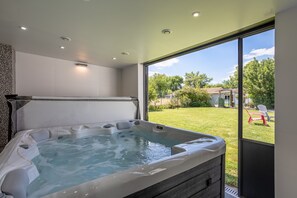 A hot tub with a view of a grassy yard and trees. - Apartment 'Au Milieu Des Vignes' with Private Terrace, Private Garden and Wi-Fi (Château-Thébaud)