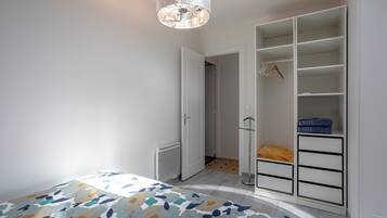 Ett sovrum med en säng, en garderob och en hängande lampa.