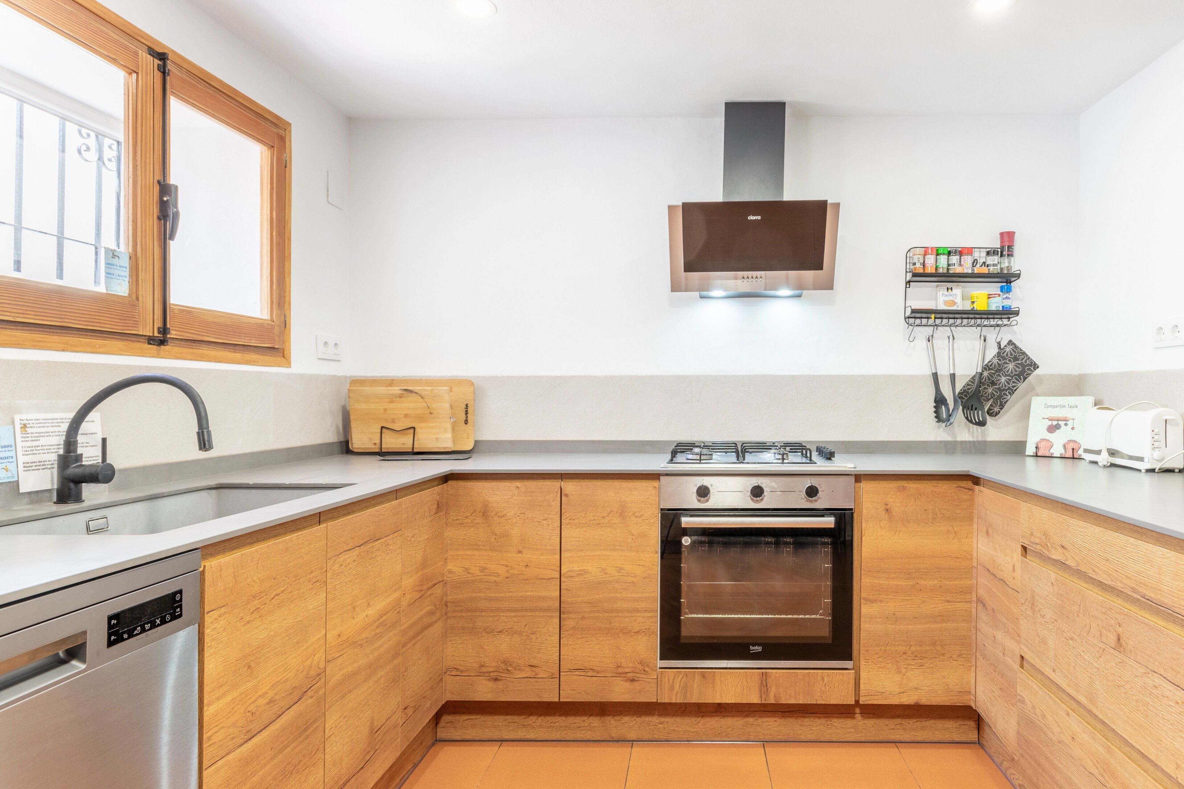 Una cocina moderna con armarios de madera, lavavajillas de acero inoxidable, estufa a gas y horno empotrado.