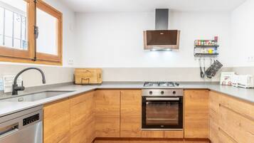 Una cocina moderna con armarios de madera, lavavajillas de acero inoxidable, estufa a gas y horno empotrado.