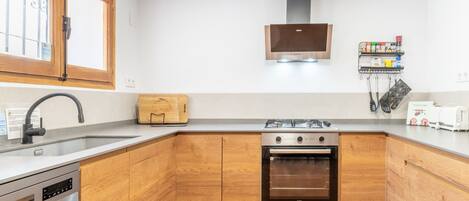 Una cocina moderna con armarios de madera, lavavajillas de acero inoxidable, estufa a gas y horno empotrado.