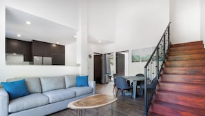 A modern living room with a grey sofa, a wooden coffee table, and a staircase with wooden steps. - Ocotal Beach House - Family Friendly & Only a Block To The Beach! (Ocotal)