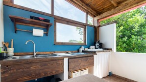 Een keuken met houten kasten, een spoelbak en een raam met uitzicht op groen.