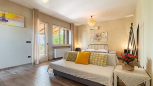 Een slaapkamer met een bed, nachtkastjes, een raam en uitzicht op groen.