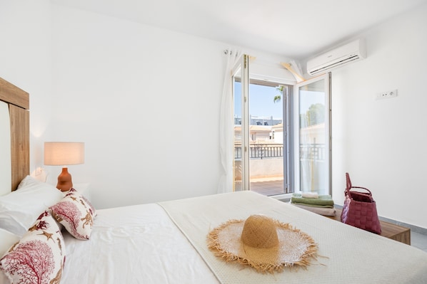 Une chambre d’hôtel comprenant un lit, une table de chevet, une lampe, une fenêtre avec vue et un appareil de climatisation.