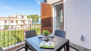 Un balcon avec une table dressée pour deux personnes, une plante en pot et une vue sur les bâtiments voisins.