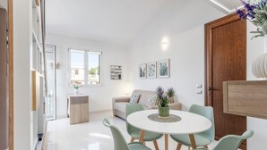 Un salon moderne avec une table de salle à manger ronde, des chaises vert clair, un canapé et un meuble en bois.