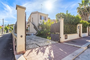 Un quartiere residenziale con ingresso carrabile recintato, vialetto lastricato e un edificio con una scala.