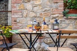 Une table dressée avec divers objets, notamment un livre, de la verrerie et des objets décoratifs, le tout mis en valeur par un mur de pierres en arrière-plan.
