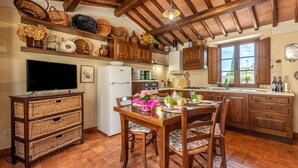 Eine Küche mit Holzausstattung, einem Esstisch, Stühlen, einem Kühlschrank und einem Fernseher.
