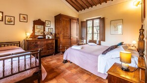 Ein Schlafzimmer mit einem hölzernen Bett, einem Schminktisch, einem Spiegel und einem Fenster.