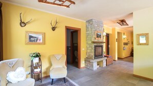 Un salón espacioso con chimenea, dos sillones, una mesa de centro y una alfombra.
