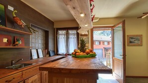 Una cocina con armarios de madera, un lavamanos de acero inoxidable y un frutero sobre la encimera.
