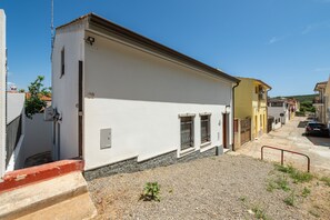 A narrow street with buildings, a gravel path, and a metal railing.