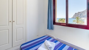 Una habitación con cama, ventana y vistas al mar, además de un armario.
