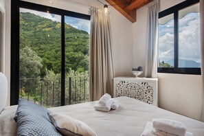 A bedroom with a bed, a bedside table, and a view of a mountainous landscape. - Apartment 'Villino Ortensia - Le Pale' with Sea View, Wi-Fi and Air Conditioning (Bogliasco)