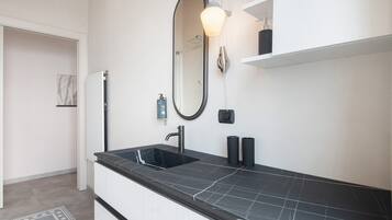 A modern bathroom with a black sink, a large mirror, and a towel rack.