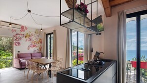 Una cocina moderna con una isla central, comedor con sillas, un sofá y ventanas amplias con vistas.