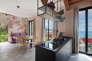A modern kitchen with a central island, dining area with chairs, a sofa, and large windows with a view. - Apartment 'Villino Ortensia - Le Pale' with Sea View, Wi-Fi and Air Conditioning (Bogliasco)