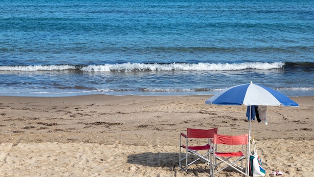 A beach with a red and blue beach chair and an umbrella. - Apartment 'Il Conte' with Mountain View, Wi-Fi and Air Conditioning (Sennori)