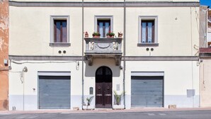 A building with a central entrance, two garage doors on either side, and a balcony with potted plants. - Apartment 'Il Conte' with Mountain View, Wi-Fi and Air Conditioning (Sennori)