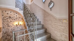 A staircase with stone walls, a wrought iron railing, and wall-mounted mirrors. - Apartment 'Il Conte' with Mountain View, Wi-Fi and Air Conditioning (Sennori)