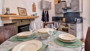A modern kitchen with grey cabinets, a marble countertop, and a dining area set with plates and glasses. - Apartment 'Il Conte' with Mountain View, Wi-Fi and Air Conditioning (Sennori)