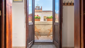 A balcony with two wooden chairs, potted plants, and a view of buildings and sky. - Apartment 'Il Conte' with Mountain View, Wi-Fi and Air Conditioning (Sennori)