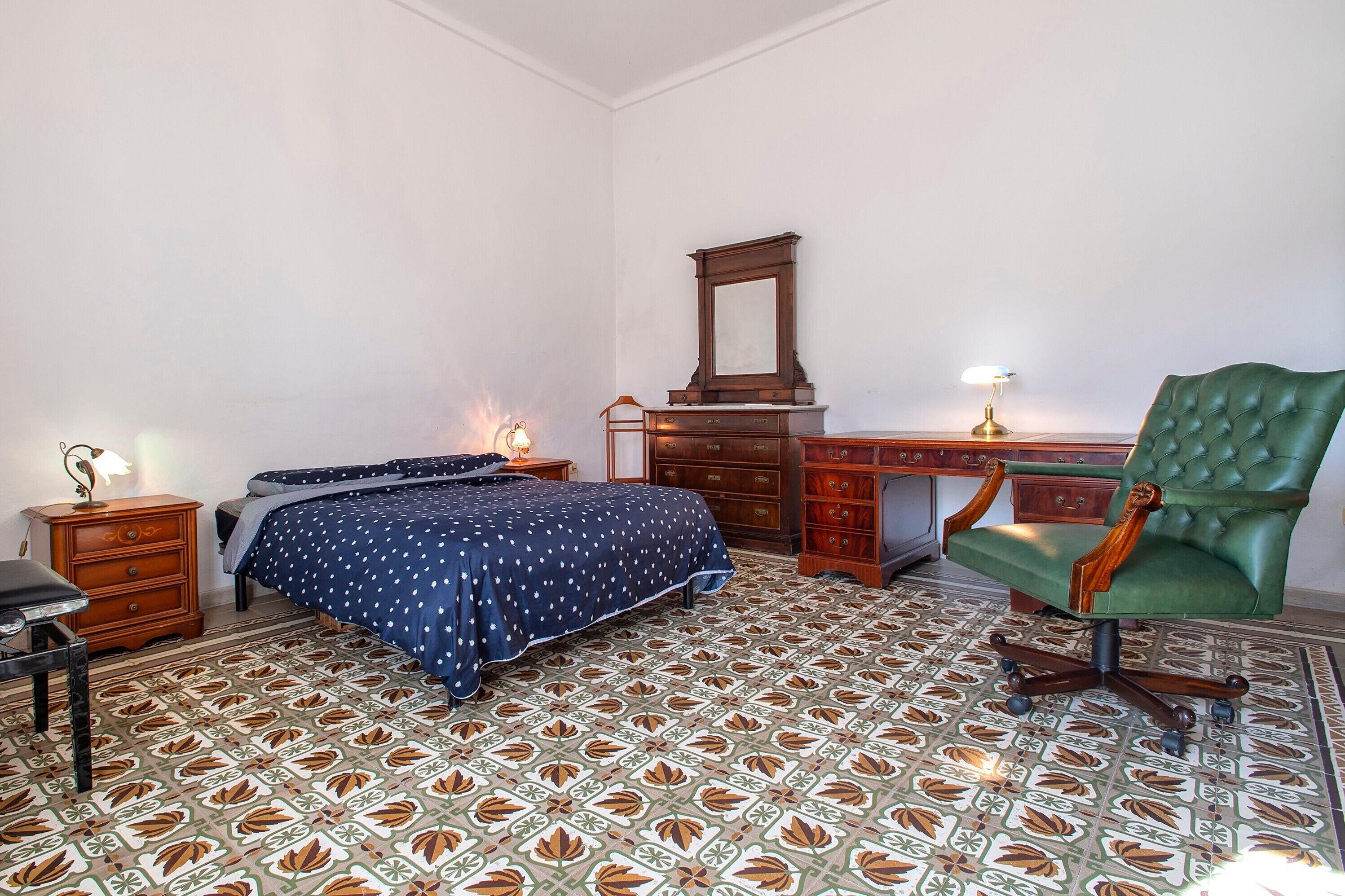 Un dormitorio con cama, cómoda, silla, escritorio y espejo.