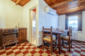 A kitchen with a checkered floor, wooden cabinets, a stove, and a dining table with chairs. - Apartment 'La Contessa' with Mountain View, Wi-Fi and Air Conditioning (Sennori)
