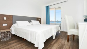 Habitación de hotel con cama, escritorio, silla y vista al mar.