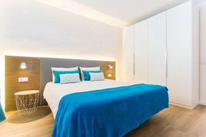 Una habitación de hotel moderna con una cama grande, una mesita de noche y un armario.