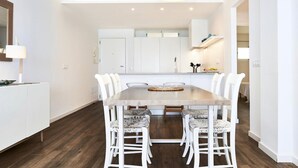Una cocina moderna con armarios blancos, una mesa de comedor de madera y sillas blancas.