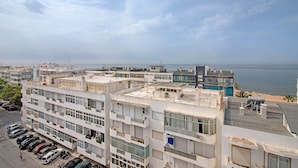 A multi-story building with balconies, a parking lot, and a view of the sea. - 'T1 with Sea View' Apartment with Wi-Fi and Air Conditioning (Quarteira)