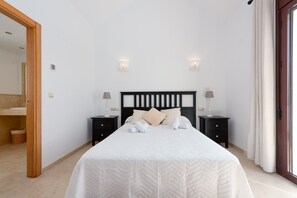 A bedroom with a bed, two bedside tables, a mirror, and a door.