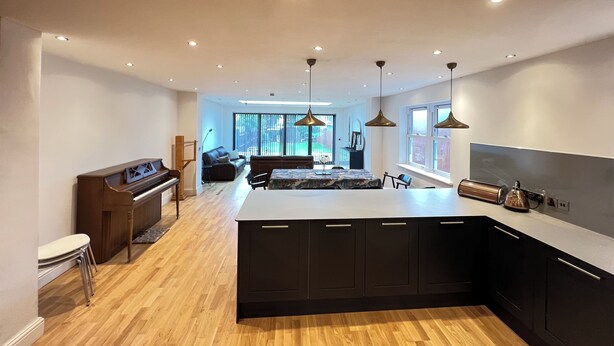 A modern kitchen with a central island, wooden flooring, and pendant lighting. - Transvaal House Ely  (Ely)