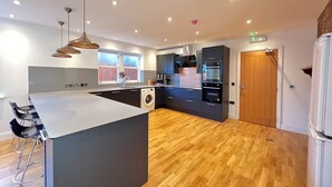 A modern kitchen with a central island, built-in appliances, and a wooden floor. - Transvaal House Ely  (Ely)